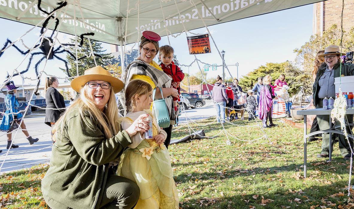 National Park Service Superintendent Susan Cook helps this little princess during the Scare in the Square program Thursday, October 31, 2024. They’re helping a little spider grab dinner with cans of Silly String! Spiders are helpful little creatures who eat annoying flies and other insects.