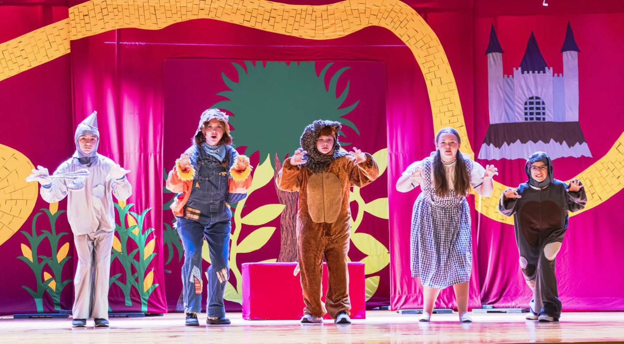 Photo by Laura Vroman Pictured at the top, are the dynamic cast of characters on their way down the Yellow Brick Road to ask the wizard to go home... for a heart...for brains...for courage. Pictured above are the munchkins celebrating the demise of the Wicked Witch.