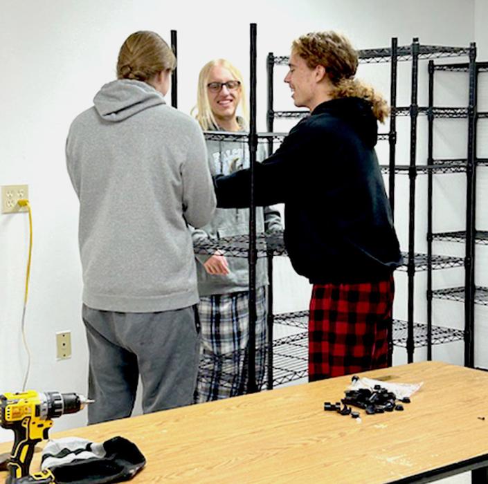 These young men from the National Honor Society and JAG help assemble shelving in the Caring Closet .