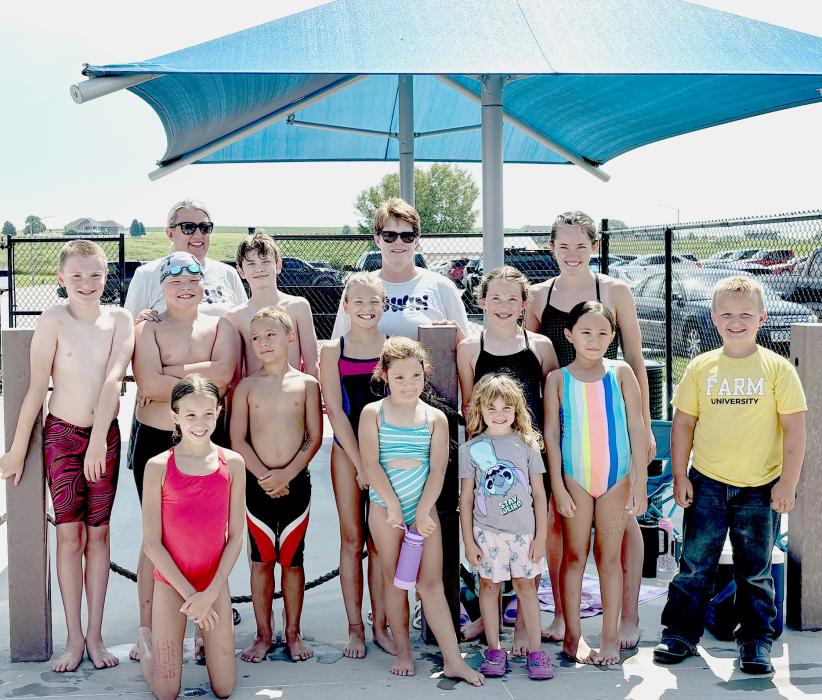 Some of the GNST Swim Team is pictured: back row, L to R: Coach Susan Tiefenthaler, Coach Shevaun Adams, and Aubrey Benson. Middle row, L to R: Ryan Adams, Henry Johnson, Reed Greenough, Sarah Burge, and Emily Benson. Front row, L to R: Brooke Nelson, River Ruby, Nova Ruby, Maddie Johnson, Adalyne Valen, and Sam Johnson. Other swimmers not pictured include: Anniyah Bailey, Tryston Bailey, Lilyan Kornely, Aiden Buckendahl, Jenalee Garwood, Sharon Araujo, Corbyn Huddle, and Eil Huddle.