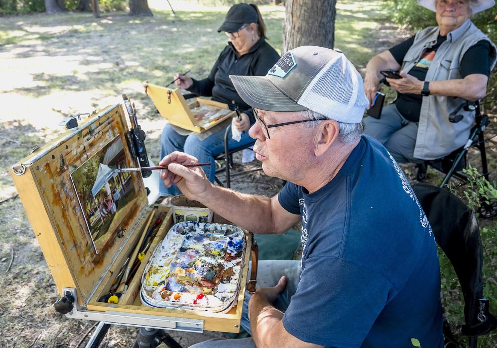 Sand Painter art member David Dorsey just whistles while he works! Pictured also are members Joan Swim and Jane Shelbourn.