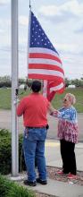 Gary Coleman and Mary Schubert Hollopeter hoist the flag at Cherry Hills Estates.