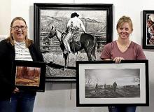 Sand Painter Art Club members are pictured with their art, Joan Swim and Chana Orton. David Dorsey’s charcoal is hanging between Swim and Orton.