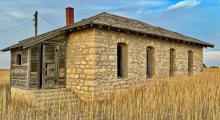 The Old Rock School sits high upon a hill, overlooking a beautiful valley whose meadows are filled with crops,cattle, and wildlife. After the meadows, Sandhills continue as far as the eye can see. Photo by Tina Boone