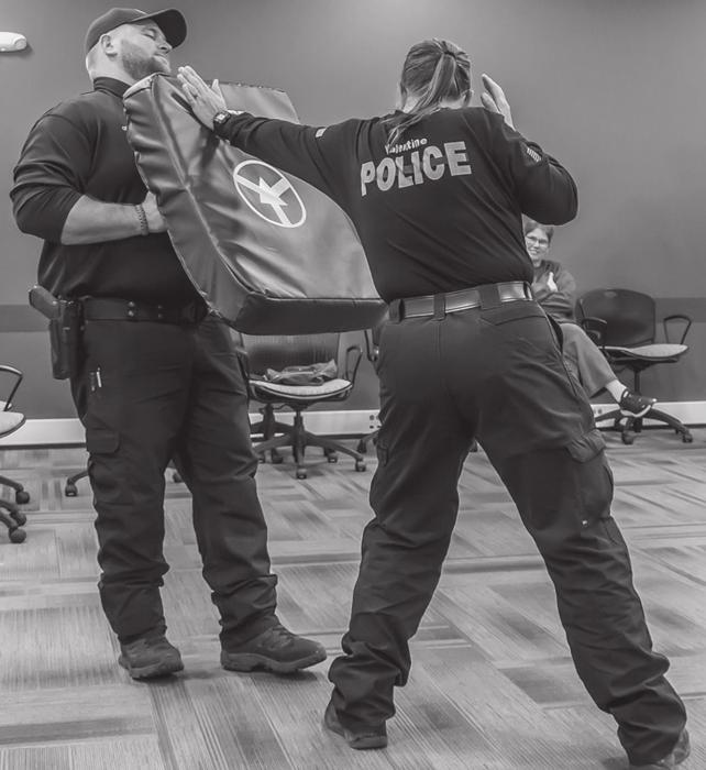 Chief Dana Miller shows the importance of leaving your thumb up as you protect yourself. Here she demonstrates a maneuver on Officer Brandon Ormesher. Her right hand is up to defend her face and head. Photo by Laura Vroman