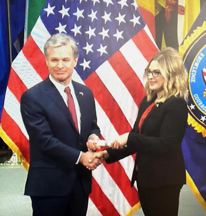 FBI Director Christopher Wray presents Raylee VanWinkle her diploma on March 17, 2022, at the FBI Academy in Quantico, VA.