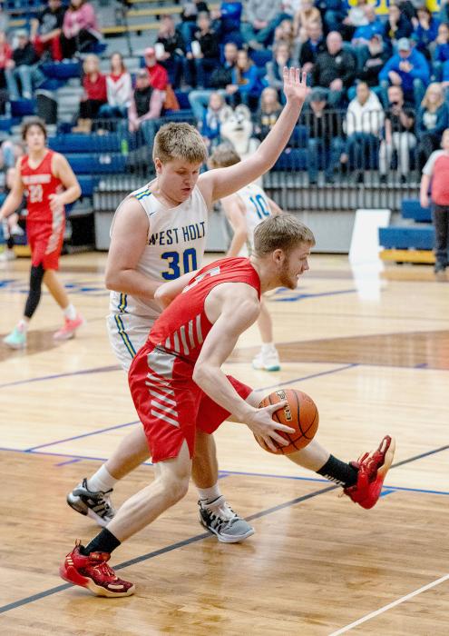 Pictured at left, Isaac Cronin goes up for points in the game against West Holt. Pictured above, Logan Muirhead brings the ball down the court. Photos by Fletcher Larsen