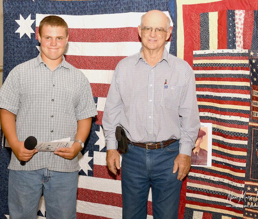 Greyson Hollopeter Swan and his mother, Annie Nielson stand- Wesley Willert presents John T. Johnson with his Quilt of Valor. ing in front of the Quilt of Valor that Greyson crafted for Tyler Hollopeter.
