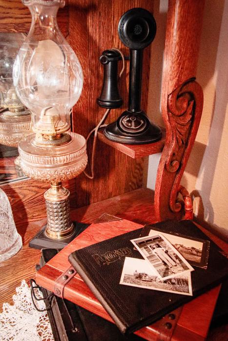 A quiet shelf of the past: an old lamp, telephone, and time worn photographs, remind us that traditions live in the everyday objects we choose to preserve, carrying stories forward long after the voices have faded. Photo by Tina Boone