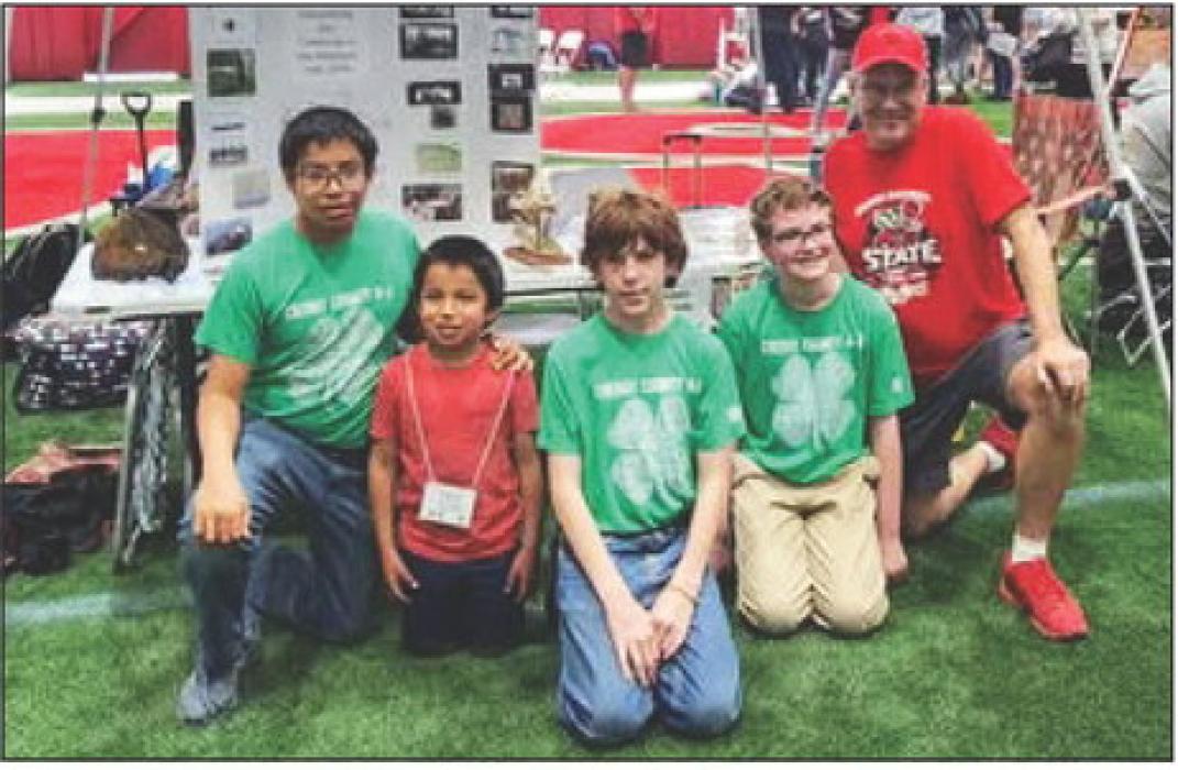 Pictured are from L to R: Luke Osnes, Tyson Osnes (future 4-Her), Tyson Cochran, Ryan Adams and Coach Andrew Utecht at their Team Pit in the UNL Cook Pavilion with their robotics project on display as they wait for competition rounds.