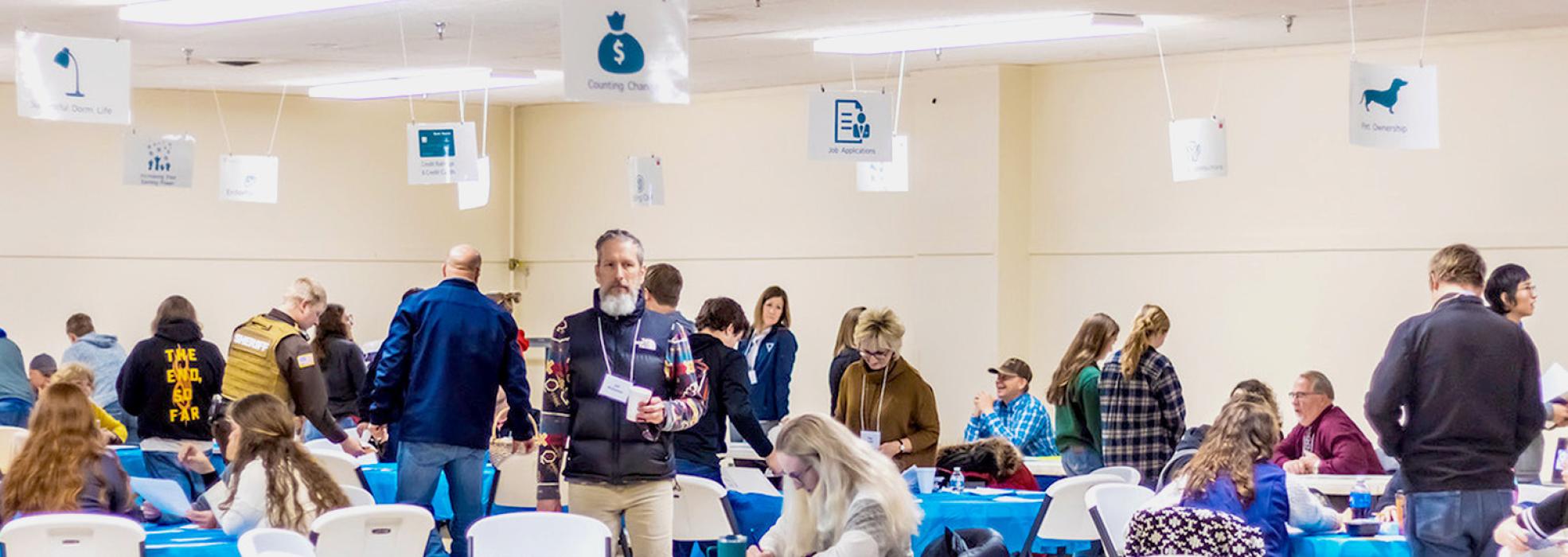 Looking up, you can see the many different stations for the youth to learn basic life skills from including pet ownership and job applications, dorm life, credit rating and credit cards to name a few. Mr. McQuistan, center, welcomed the students to the program. Photos by Laura Vroman