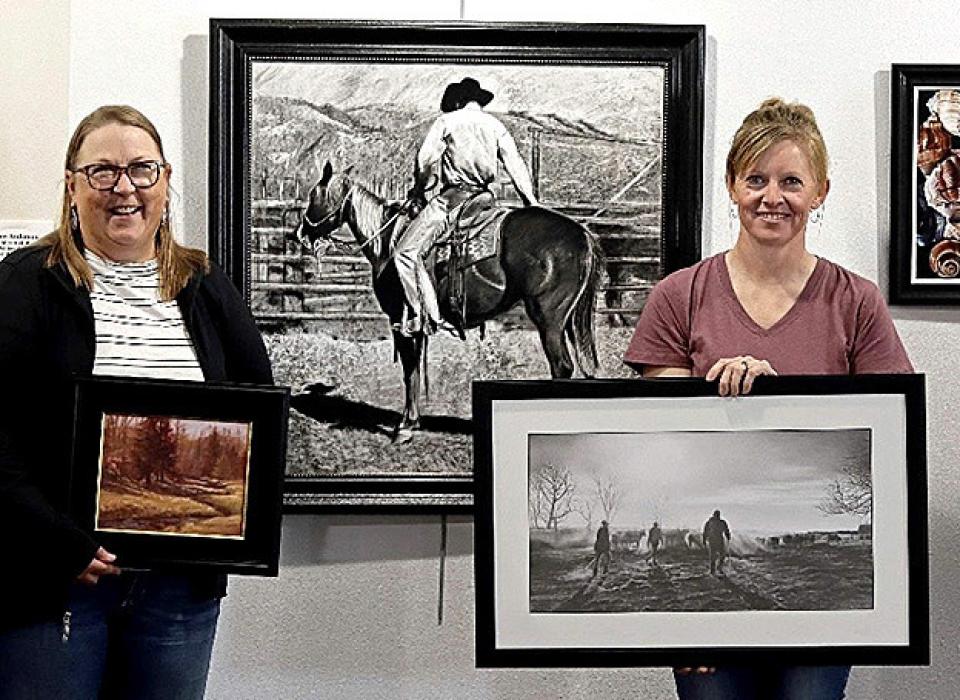 Sand Painter Art Club members are pictured with their art, Joan Swim and Chana Orton. David Dorsey’s charcoal is hanging between Swim and Orton.