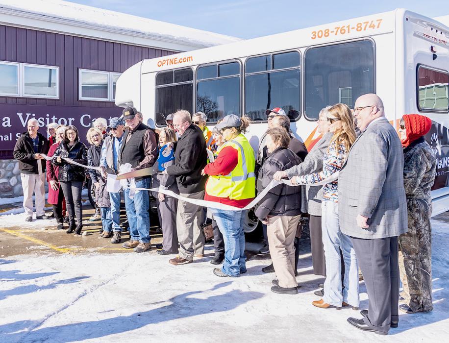 Open Plains Transit held their Ribbon Cutting at the Nebraska Park Service’s Niobrara Visitor’s Center. City Manager Shane Siewert uses giant scissors to cut the ribbon on the brand new service that will pick up and drop people off Monday through Friday. Photo by Laura Vroman