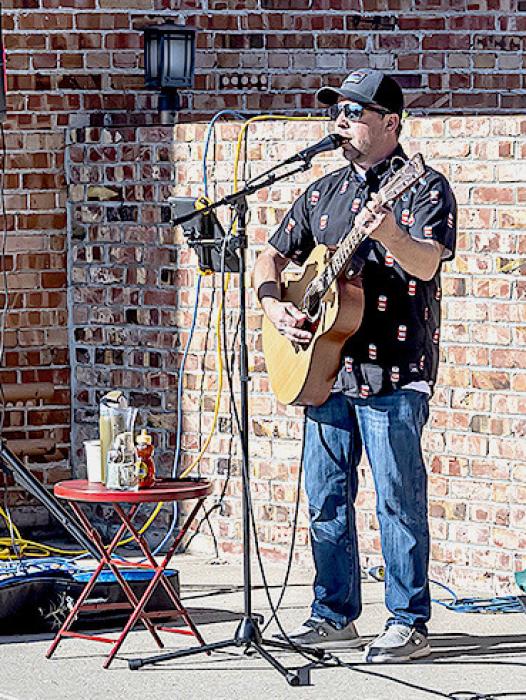 Above, Outside Broken Spoke Boutique, Sand Painter artist Joan Swim visits while working on an oil painting. At lower right, Grant Bitner entertains with his art form, at Security First Bank - which was set up for with picnic tables to enjoy good food and beverages.