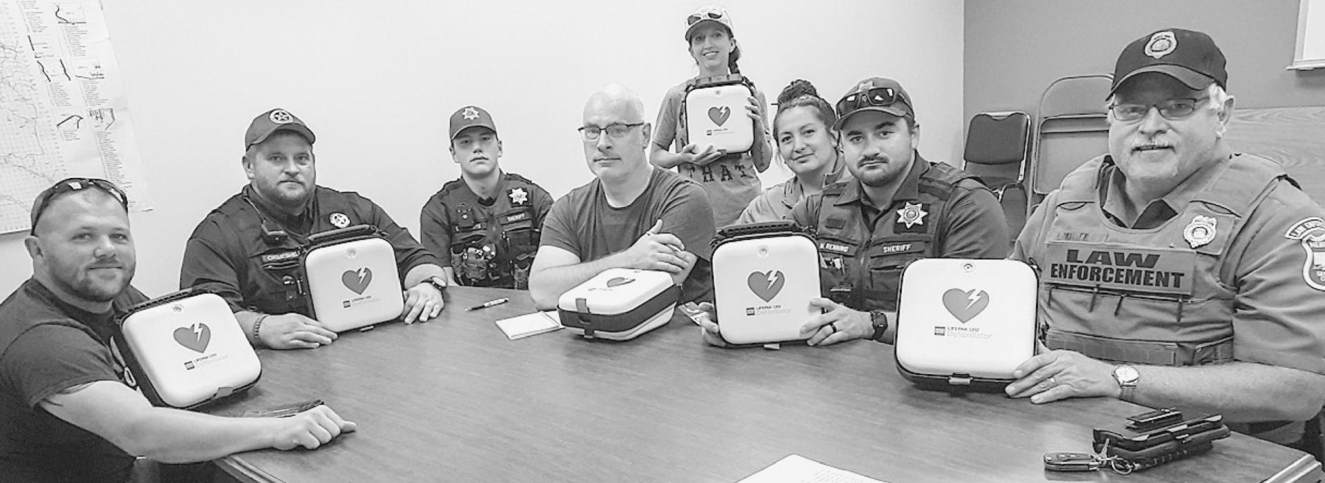 Law Enforcement officers are pictured L to R: Officer Ryan McSweeney, Officer Brandon Ormesher, Deputy Trevor Wilcutts, Lt. Jamon Slama, Officer Jasmine Hoefs, Valentine Police Administrative Assistant and AED/CPR instructor Bobbi Johnson, Deputy Max Renning and Conservation Officer Frank Miller. Every officer in Cherry County received an AED for their patrol vehicle!