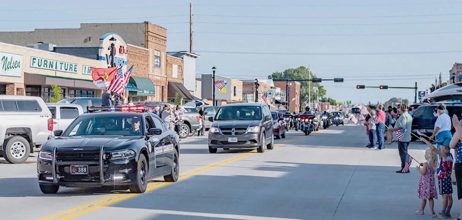 PFC Dale Thompson is ushered down Valentine’s Main Street, Tuesday, June 27, 2023, as well wishers show their patriotism with flags, which are also on the street lights.