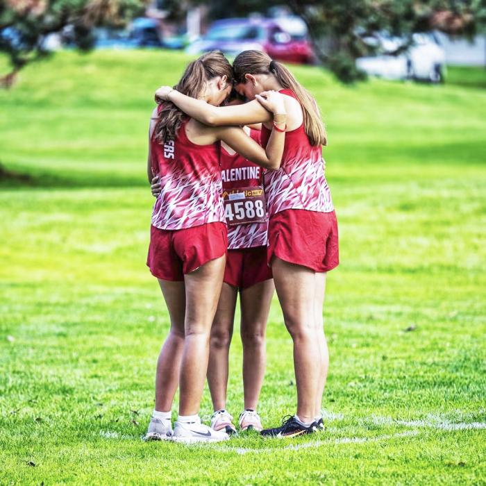 Kealy Titus, Taylie Fletcher, and Mariana Azarcoya huddle for a prayer before running. Photos by Chris Mosner