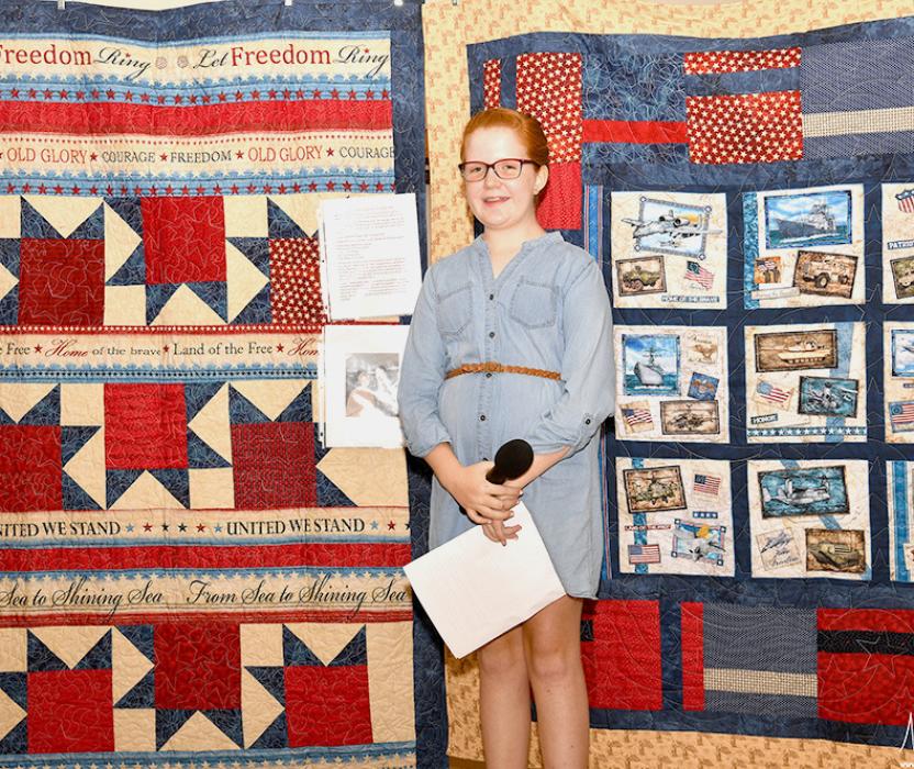 Brooke Brashears stands in front of the Quilt of Valor she crafted for George Castelli.