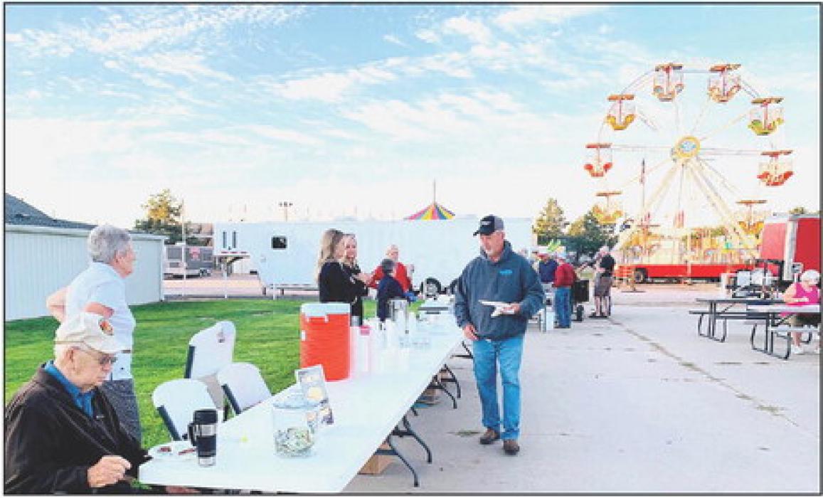 Amusement rides highlight the background as the Cherry County Hospital Foundation is grilling their pancakes golden and ready to serve.