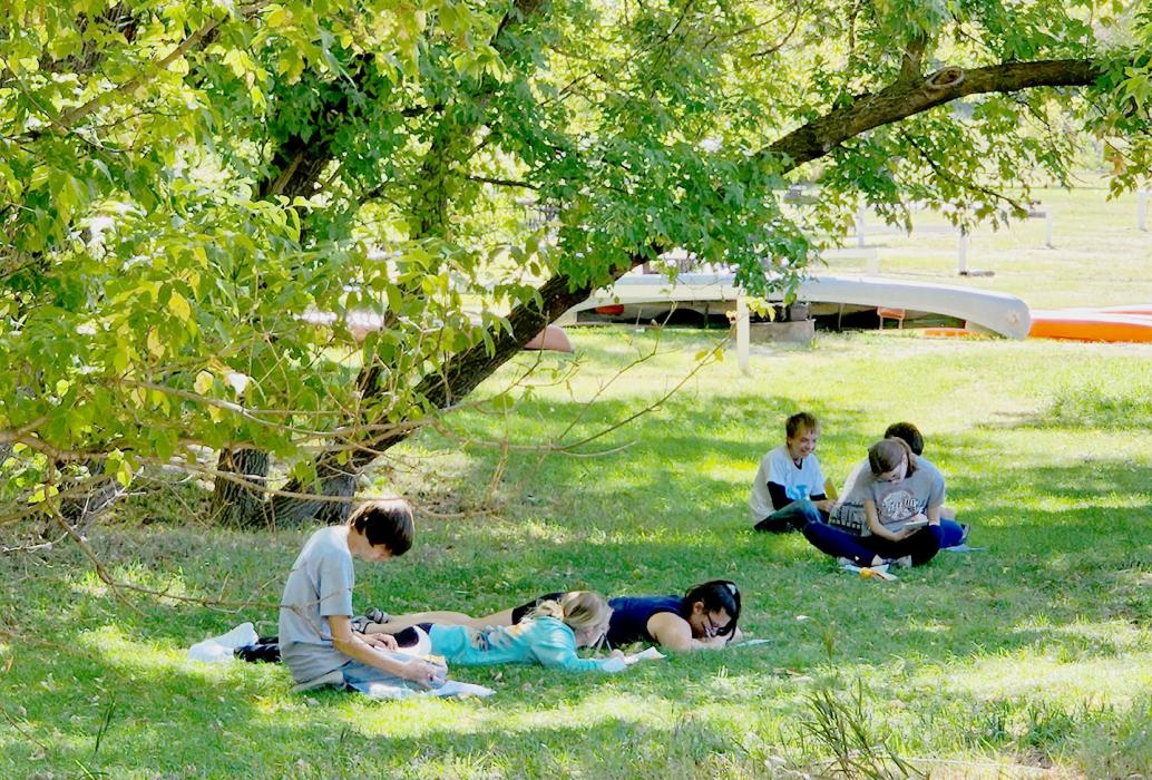 Students write the Niobrara with the river in the background during the Write the River: Creative Writing Float and Art Experience.