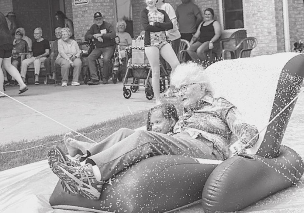 Above, Gloria Andrews goes down the water slide with one of her great grandchildren visitors.