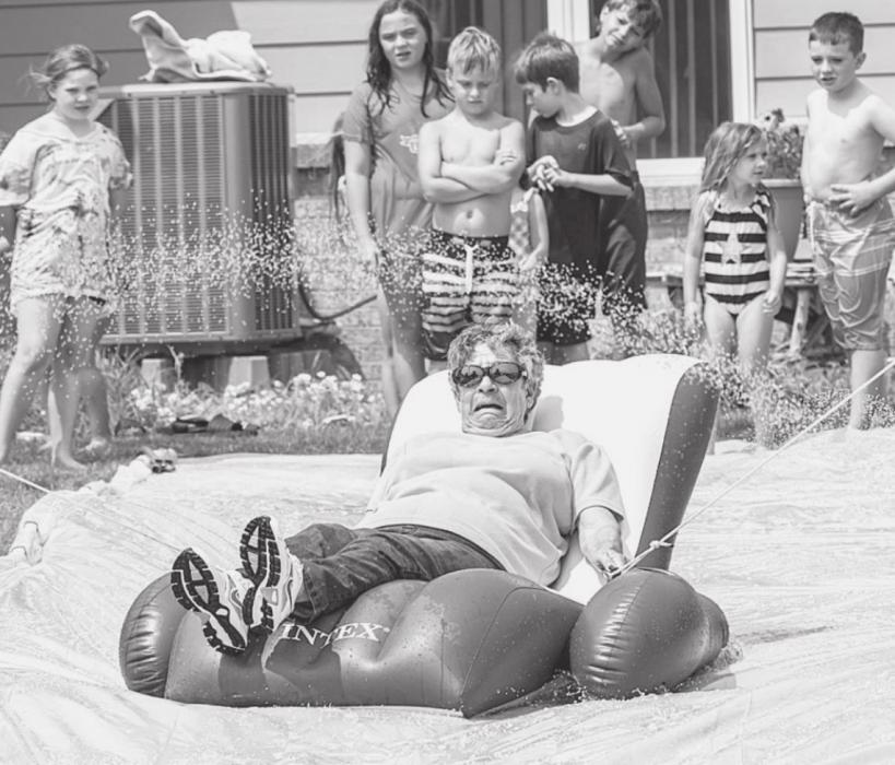 Carol Fullerton is going under the sprinklers as she is being pulled along by Gary and Crystal on the homemade slip n slide.