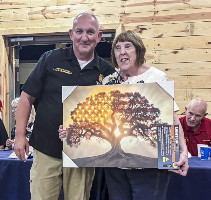 Dept Nebraska Commander Gallino “toasts” State Auxiliary President Gerlt with a beautiful light up patriotic art piece during the Homecoming gathering October 10, at the Vets Club in Valentine. Photo by Jean Vackiner