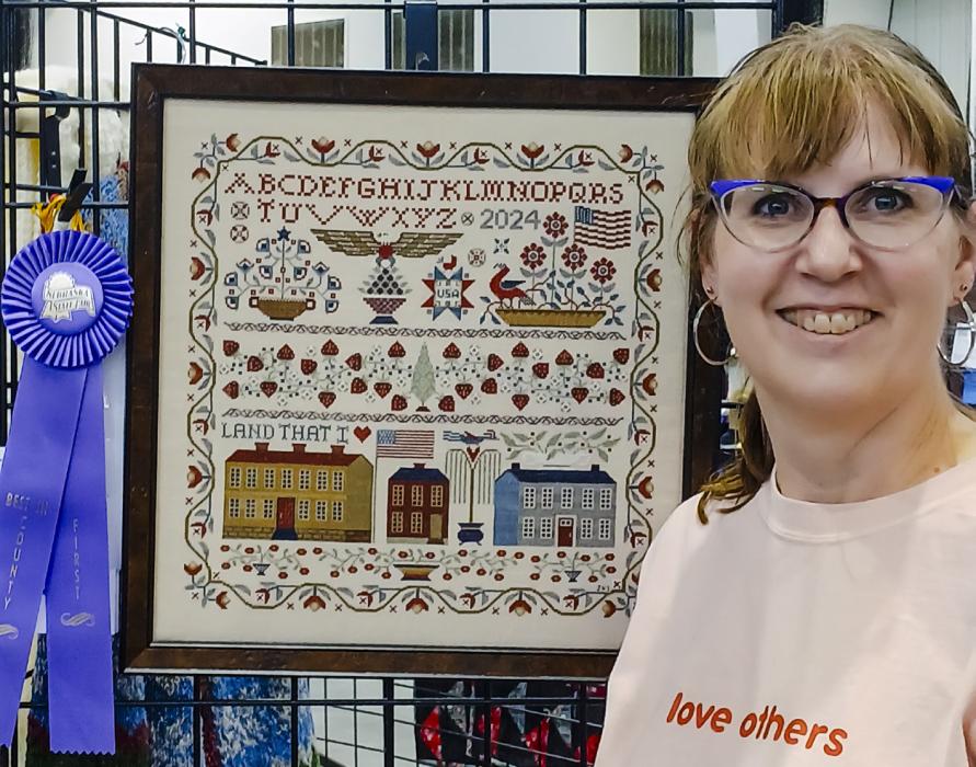 Janell Stoeger’s cross stitch project received first place at the Nebraska State Fair in Best in County category. She stitched Teresa Kogut’s Land That I Love pattern on 40 count (20 stitches per inch) linen and called for flosses.
