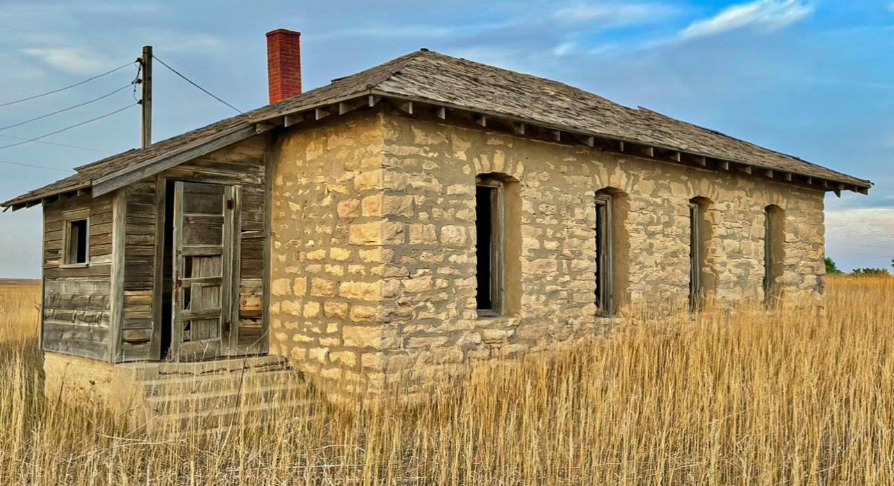 The Old Rock School sits high upon a hill, overlooking a beautiful valley whose meadows are filled with crops,cattle, and wildlife. After the meadows, Sandhills continue as far as the eye can see. Photo by Tina Boone